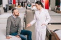 selective focus of male customer and shop assistant in white coat in furniture shop with arranged