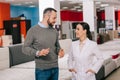 selective focus of male customer and shop assistant in white coat in furniture shop with arranged