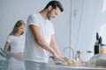 selective focus of man cutting fruits at counter with pregnant wife behind in kitchen Royalty Free Stock Photo