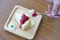 In selective focus a man hand holding a spoon with a piece of chesse cake,wooden plate