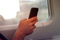 Selective focus of man hand with smart phone which he is a Freelancer as working by moblephone in the train -Trip travel and