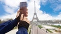 Selective focus of man hand with he is using smartphone take picture at View of Eiffel Tower with blue sky background in  Paris, Royalty Free Stock Photo