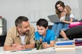 selective focus of man helping son with homework while mother and daughter using laptop on sofa together Royalty Free Stock Photo