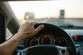 Selective focus man`s hand on steering wheel, driving a car at sunset. Travel background Royalty Free Stock Photo