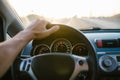 Selective focus man`s hand on steering wheel, driving a car at sunset. Travel background Royalty Free Stock Photo