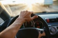 Selective focus man`s hand on steering wheel, driving a car at sunset. Travel background Royalty Free Stock Photo