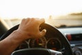 Selective focus man`s hand on steering wheel, driving a car at sunset. Travel background Royalty Free Stock Photo