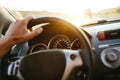 Selective focus man`s hand on steering wheel, driving a car at sunset. Travel background Royalty Free Stock Photo