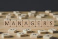 Focus of managers inscription on cubes surrounded by blocks with letters on wooden surface isolated on black