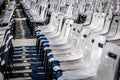 Selective focus of many gray chairs in straight lines on a cobblestone square.