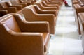 Selective focus of many leather chairs or couches in rows in perspective view with blurred background of people legs who is Royalty Free Stock Photo