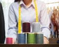 Selective focus of many spool of threads and blurred image behind of midsection of young female tailor