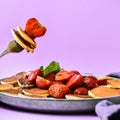 Selective focus on Maple syrup pouring on fork with tiny pancakes and strawberry. Pancake porridge, mini pancakes cereal in a bowl Royalty Free Stock Photo