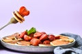 Selective focus on Maple syrup pouring on fork with tiny pancakes and strawberry. Pancake porridge, mini pancakes cereal in a bowl Royalty Free Stock Photo