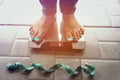 Selective focus of measure tape which woman feet look Lose weight concept  on a scale measuring kilograms on floor background Royalty Free Stock Photo