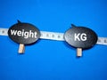 Selective focus.Measuring tape with word weight and kg on a wooden board with blue background.Shot were noise and film grain.