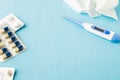 Selective focus on medical pills, used tissue and thermometer on blue background, copy space