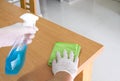 Selective focus of men hand wearing glove and use alcohol sanitizer, disinfectant spray on wood desk surface. Deep clean for Royalty Free Stock Photo