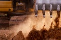 Selective focus on metal bucket teeth of backhoe digging soil. Backhoe working by digging soil at construction site. Crawler Royalty Free Stock Photo