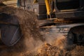 Selective focus on metal bucket teeth of backhoe digging soil. Backhoe working by digging soil at construction site. Crawler Royalty Free Stock Photo