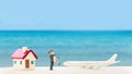 Selective focus of miniature tourist couple with plastic toy airplane and home model over blurred swimming pool