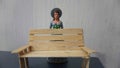 Miniature toy doll women in dress with hat and handicrafts bench chair