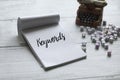 Selective focus of miniature typewriter,alphabet beads and notebook written with Keywords on white wooden background Royalty Free Stock Photo