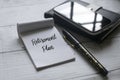 Selective focus of mobile phone,notebook,pen and paper written with Retirement Plan on white wooden background Royalty Free Stock Photo