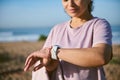 Selective focus on modern smart watch in the hand of sportswoman checking pulse on mobile app while working out outdoor Royalty Free Stock Photo