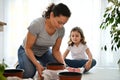 Selective focus: mom and daughter planting seeds and repotting houseplants at springtime