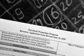 Selective focus monochrome photo of paycheck protection program borrower application form revised, on a background of chalk board