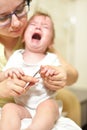 Selective focus The mother cuts the child`s toenails on the arm with baby safe scissors. Self care authentic concept. Mother care