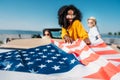 selective focus of multiethnic young women resting in car with american flag