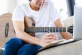 Selective focus of musician's hand composing music with acoustic guitar in living room