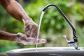 Selective focus of the old man hand image washing with dishwashing liquid and clean water on the sinks in the house near garden to