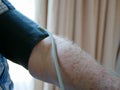 An old man`s arm with a pressure cuff on checking his blood pressure at home by himself Royalty Free Stock Photo