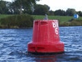 Selective focus of an old red buoy floating in blue waves with green vegetation in the background Royalty Free Stock Photo