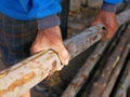 Old worker`s hands grasping and carrying woods logs at a wooden log store