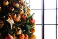 Selective focus. Ornaments made of golden balls, beads and a big star on the Christmas tree by the window. New Year`s background Royalty Free Stock Photo