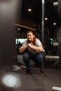 Focus of overweight girl squatting with clenched hands in gym