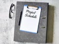 Selective focus paper clipboard written project schedule with pen,ring file and eye glasses.