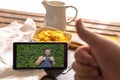 Selective focus of a person having breakfast with golden milk and cornflakes while making a video call with a mobile phone to a