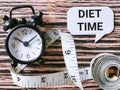 Selective focus phrase diet time written on bubble speech with alarm clock and measuring tape. Royalty Free Stock Photo