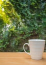 A selective focus picture of a cup of coffee on wooden table in green garden