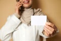 Closeupof a plastic blank white card on the hand of a female muslim doctor wearing a hijab talking on the phone. Copy space for