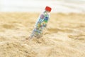 Selective focus of a plastic bottle filled with microplastics in the sandy beach