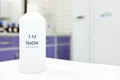 Selective focus of a plastic bottle of sodium hydroxide solution or NaOH chemical reagent. Chemistry research laboratory. Royalty Free Stock Photo