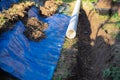 Selective focus plastic sewage pipes PVC, blue tarp with dirt, black mixing tub, pipe ready to laying, buried in ground trench,