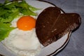 Plate with tasty traditional breakfast with fried egg, slices of heard-shaped bread and greenery Royalty Free Stock Photo