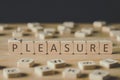 Focus of pleasure lettering on cubes surrounded by blocks with letters on wooden surface isolated on black